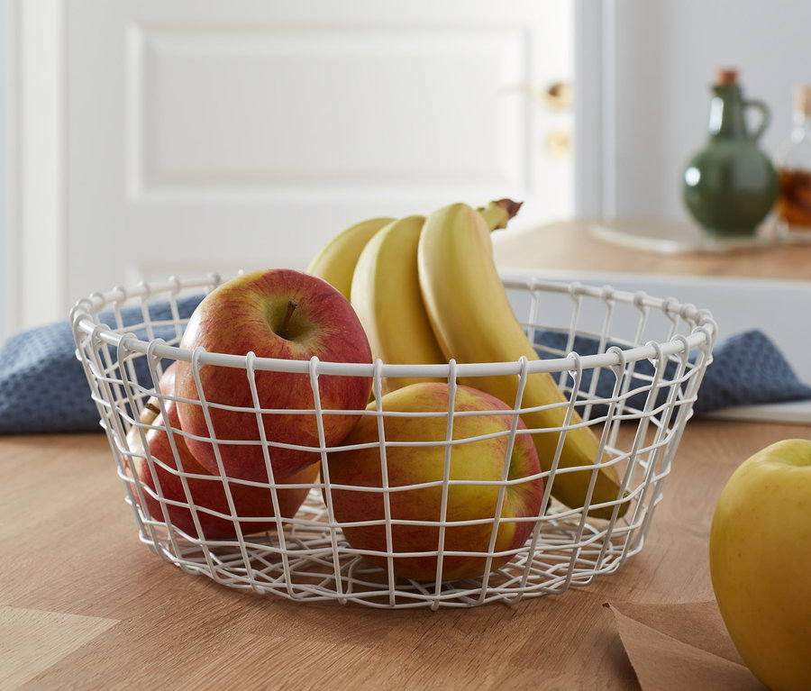 Jablka a banány v drátěné míse.