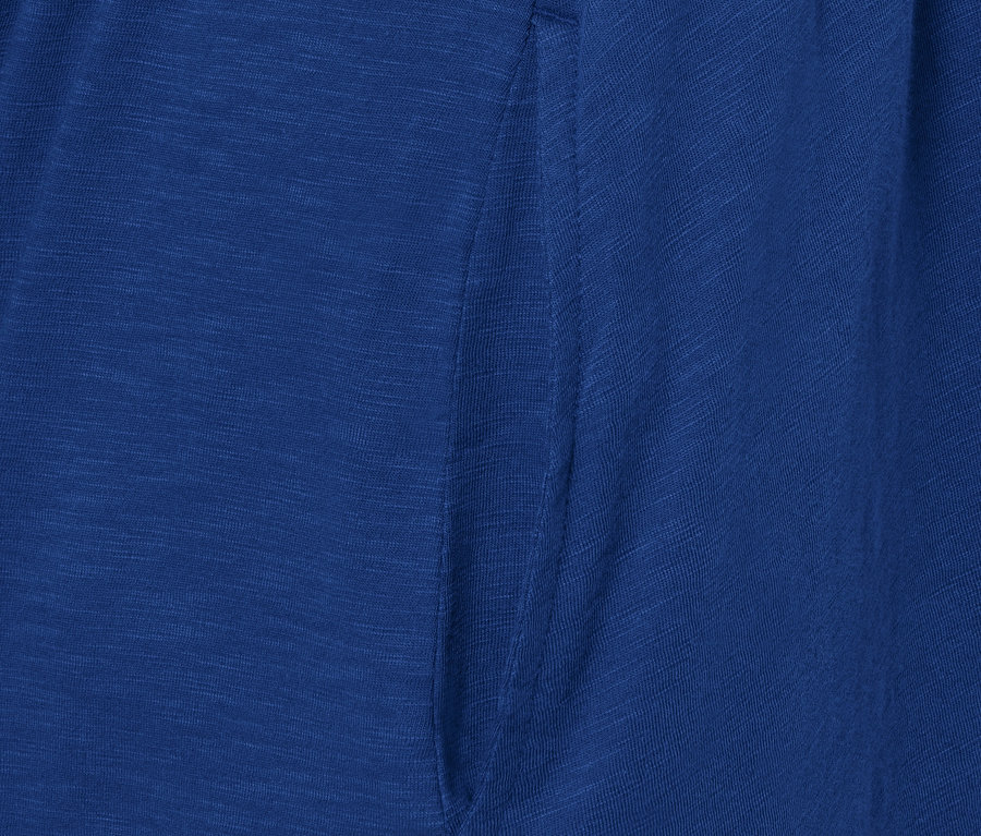Detail modrých žerzejových šatů s kapsou.