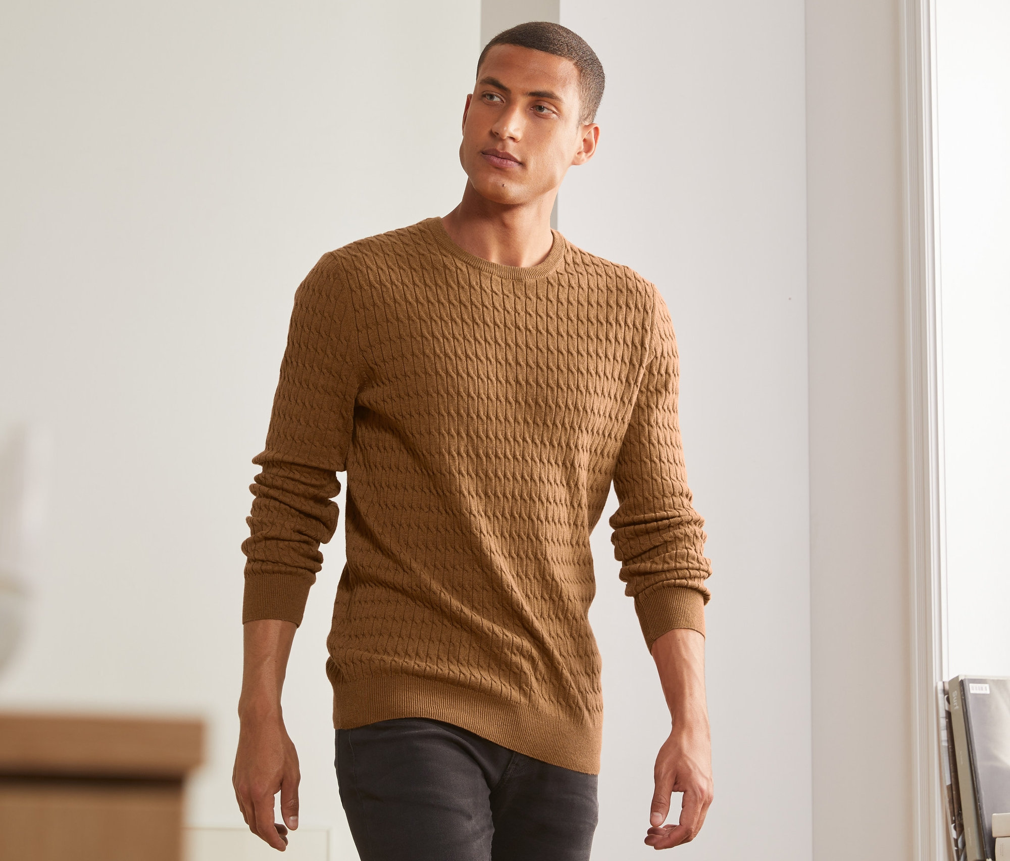 Muž má na sobě hořčicově žlutý melírovaný pletený svetr.