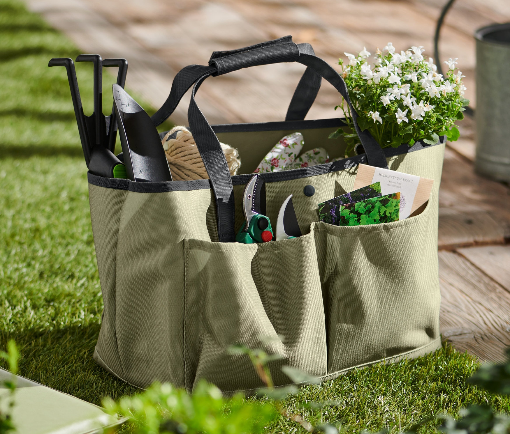 Zahradní nářadí v tašce na zahradní nářadí na trávě.