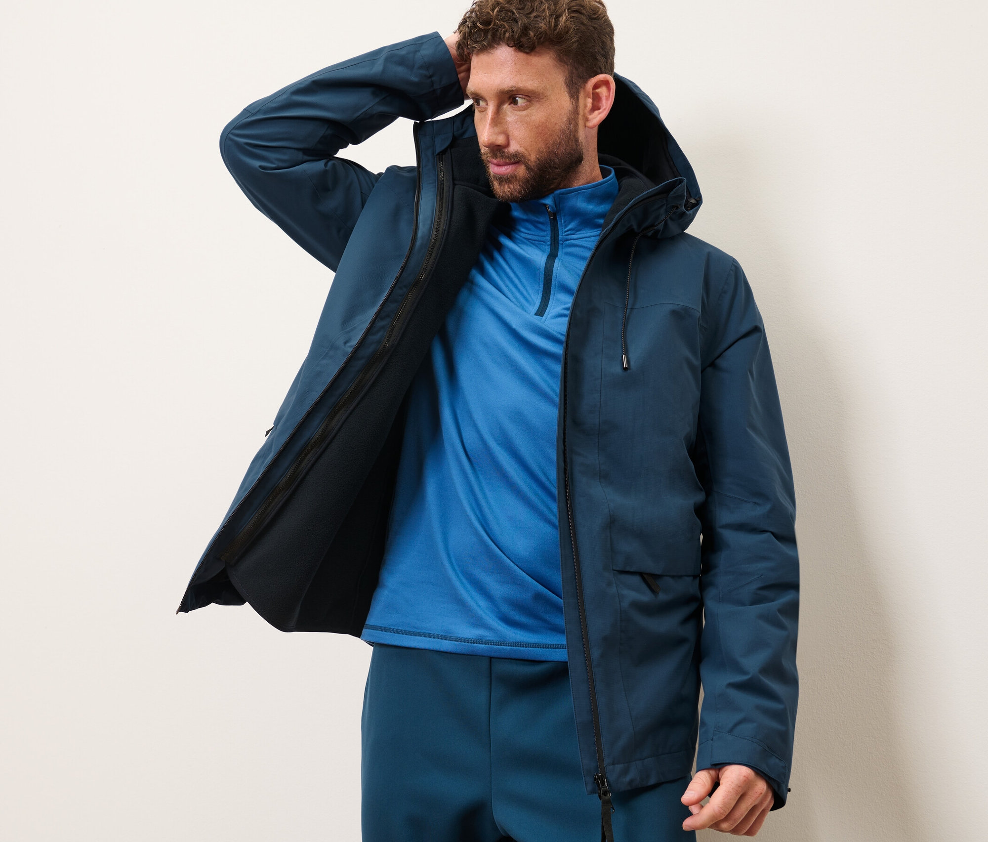 Muž pózuje v outdoorové bundě s vestou.