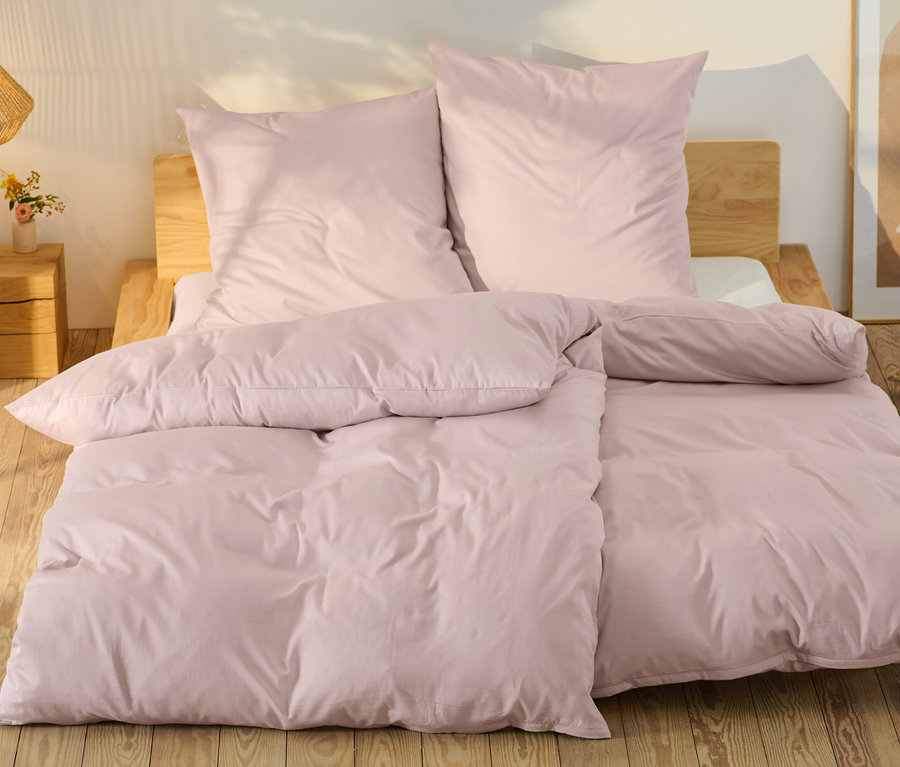 Růžové saténové povlečení standardní a nadměrné velikosti na posteli.