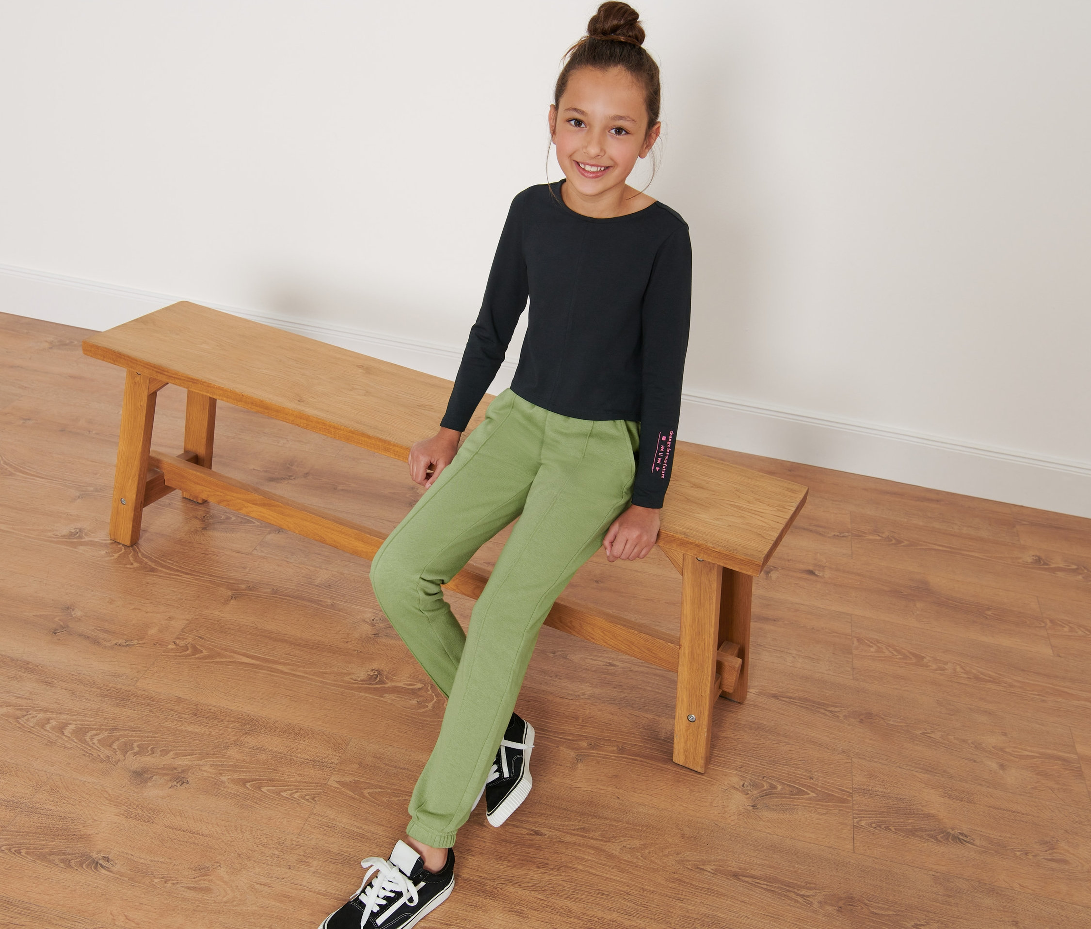 Dívka sedí na lavici a má na sobě dětské tepláky.