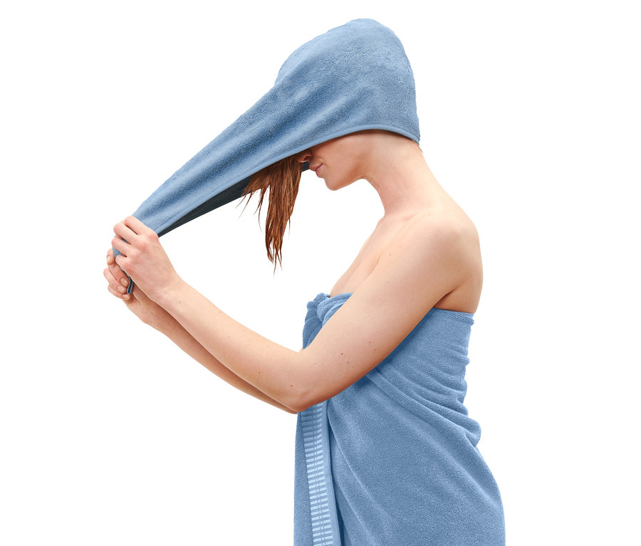 Žena si dává na hlavu modrý ručníkový turban.