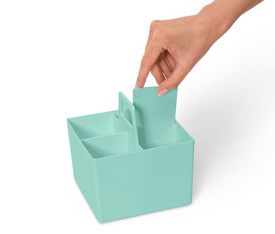 Ruka vkládá přepážku do světle modrého organizéru s několika přihrádkami.