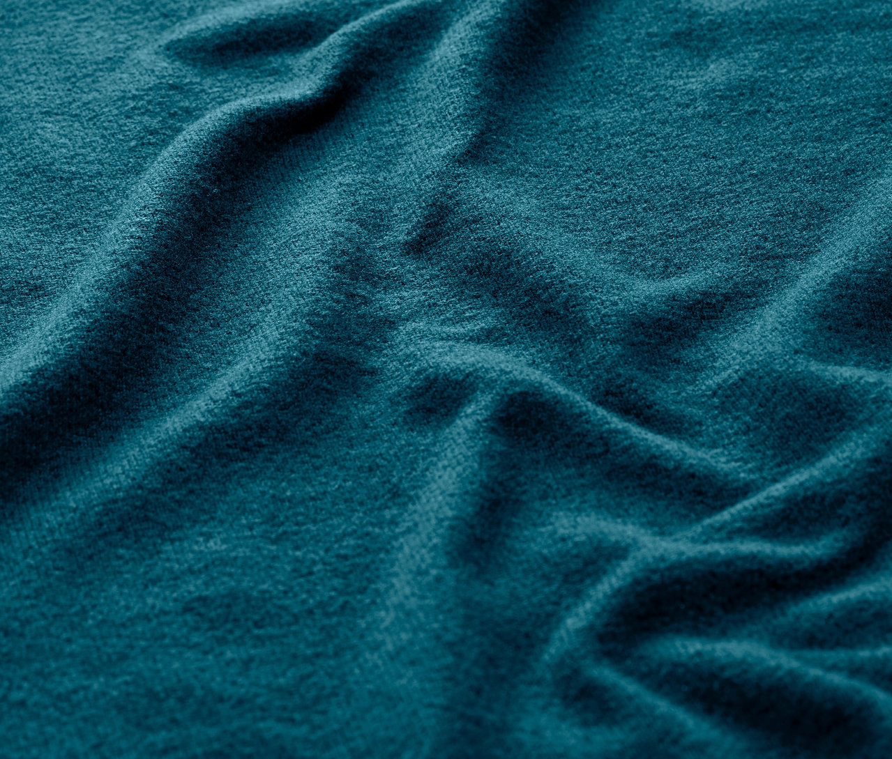 Detailní záběr na sportovní triko s dlouhým rukávem, super jemné, v petrolejové barvě.