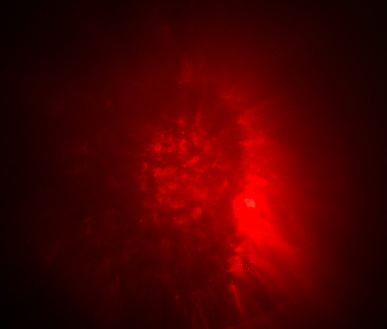 Abstraktní obraz s červenými skvrnami a světelnými efekty.