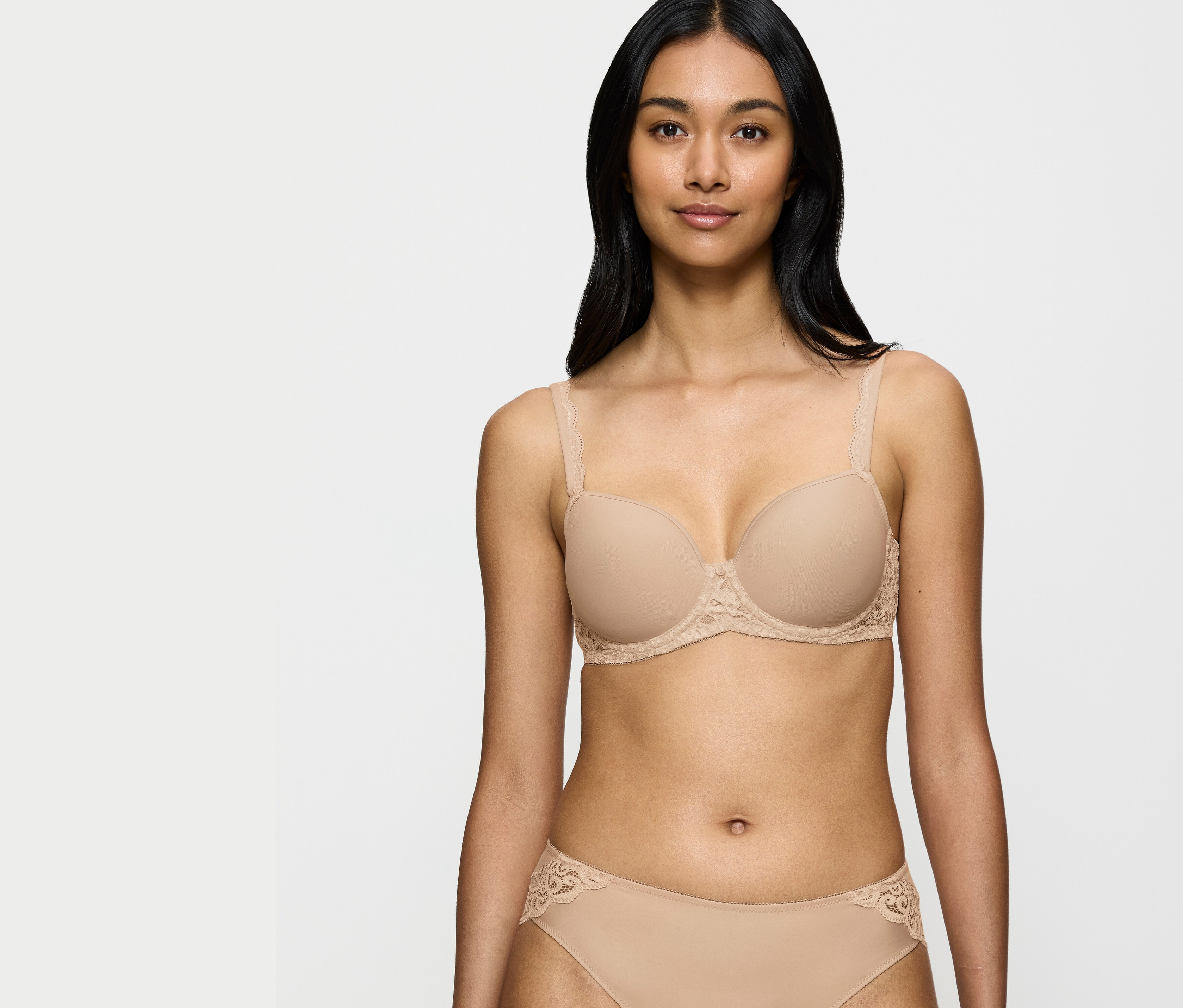 Žena má na sobě béžovou podprsenku a kalhotky s krajkovými detaily.
