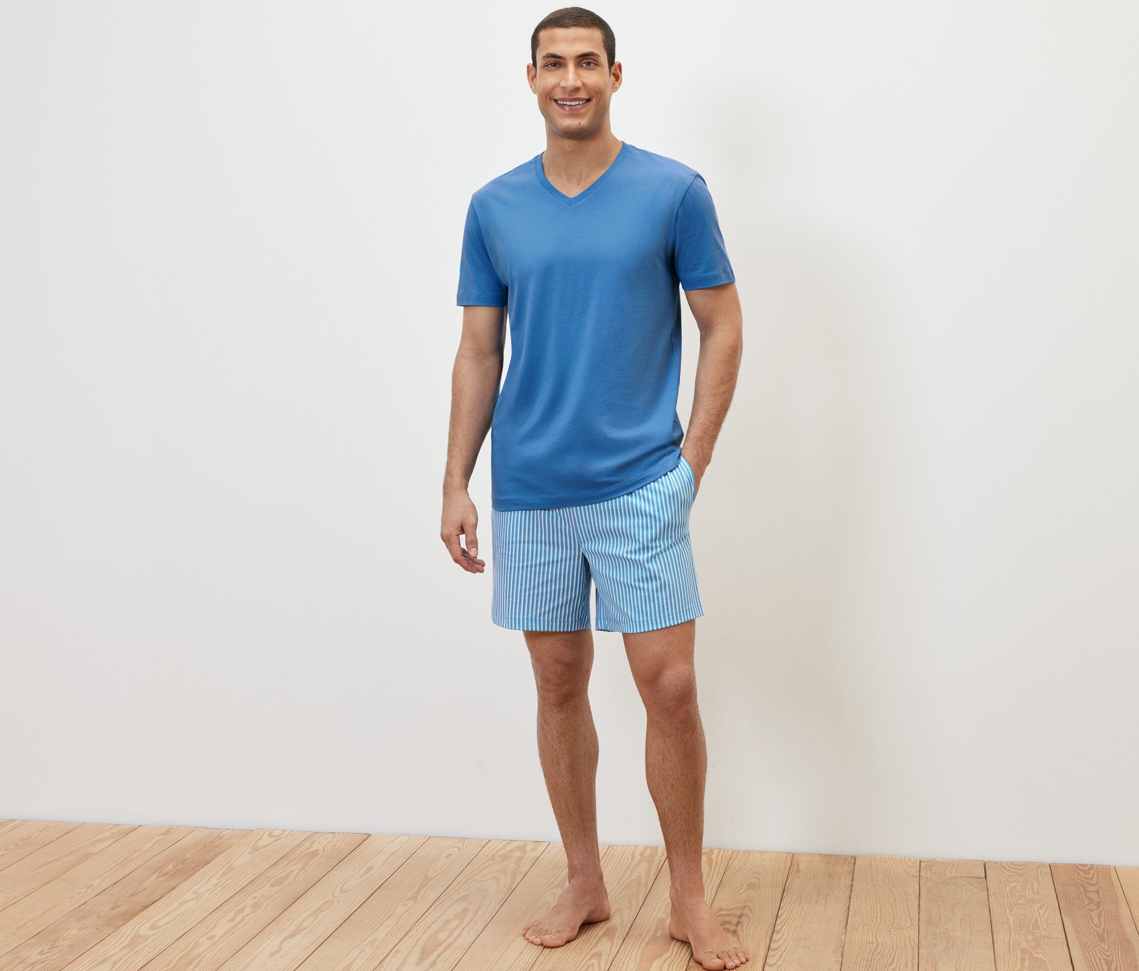 Muž pózuje v krátkém pyžamovém kompletu.