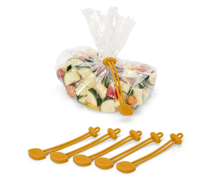 Kostky cukety, mrkve a papriky v plastovém sáčku, uzavřeném žlutou silikonovou stahovací páskou s motivem listu. Pod sáčkem jsou čtyři žluté silikonové pásky.