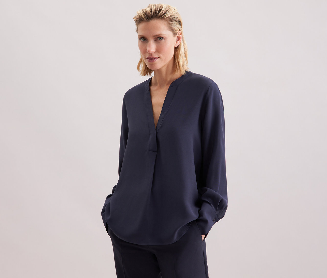 Žena má na sobě tmavě modrou tuniku Seidensticker z viskózy a kalhoty.
