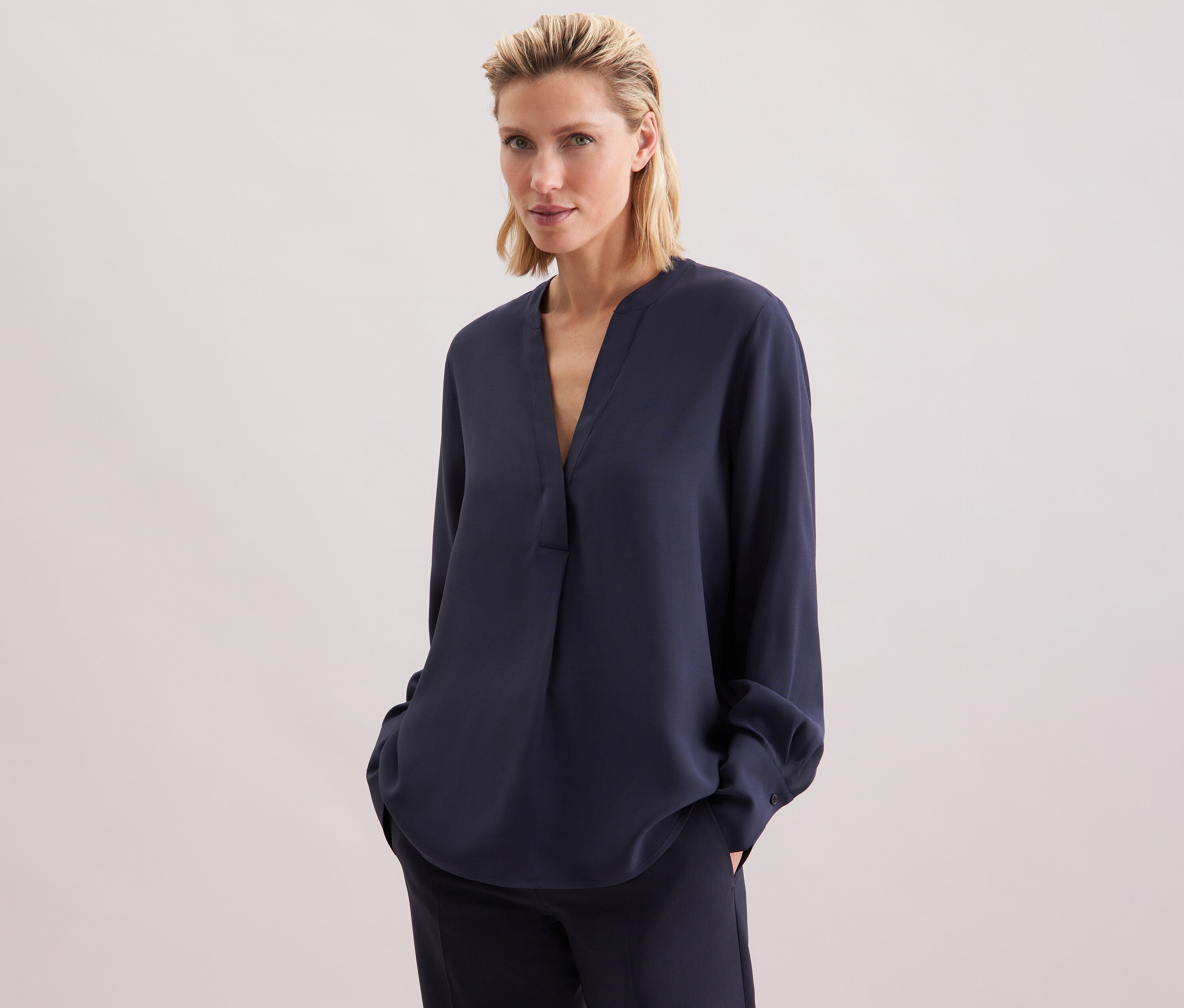 Žena má na sobě tmavě modrou tuniku Seidensticker z viskózy a kalhoty.