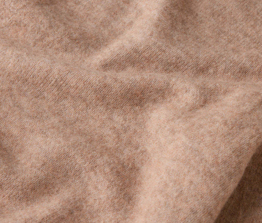Detail béžové vlněné látky se záhyby.