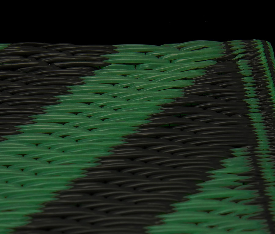 Detailní záběr na fluorescenční stanový koberec se střídajícími se zelenými a černými pruhy.