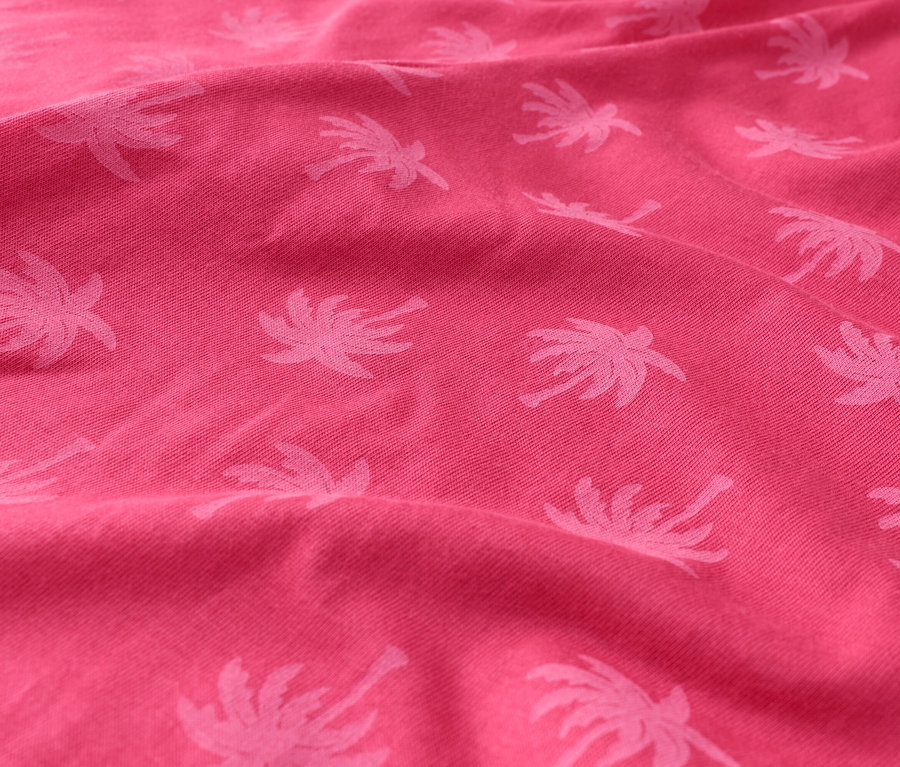 Detail růžové látky s palmovým vzorem.
