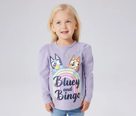 Dívka má na sobě fialové dětské triko s dlouhým rukávem NAME IT »BLUEY« s potiskem Bluey a Bingo.