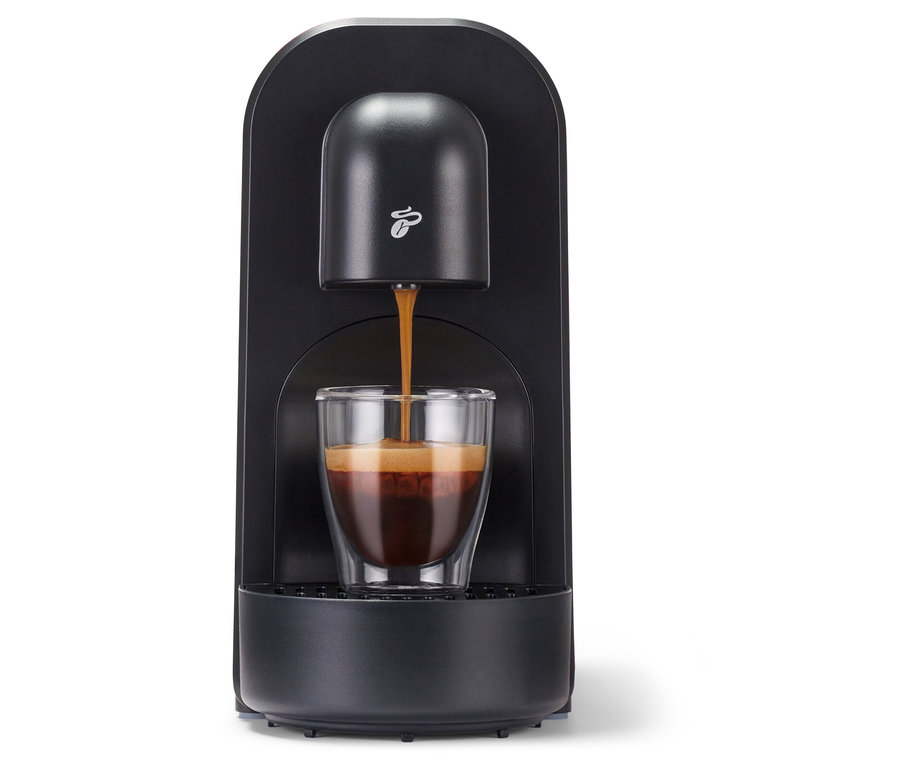 Espresso teče z černého kávovaru Cafissimo now red do sklenice.