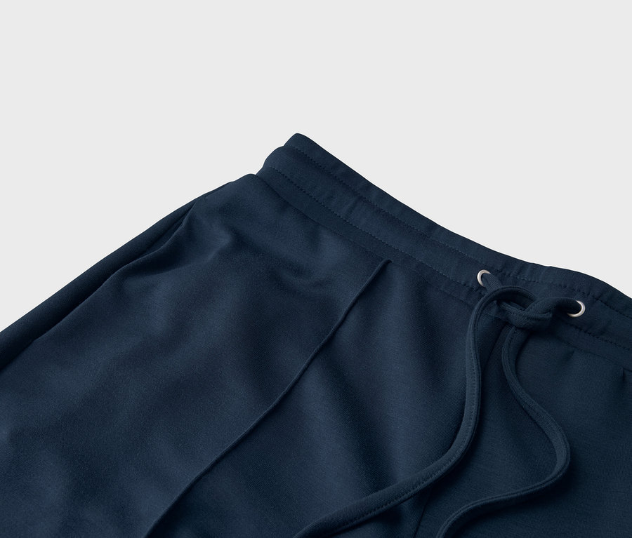 Detailní záběr na tmavě modré tepláky se stahovací šňůrkou.