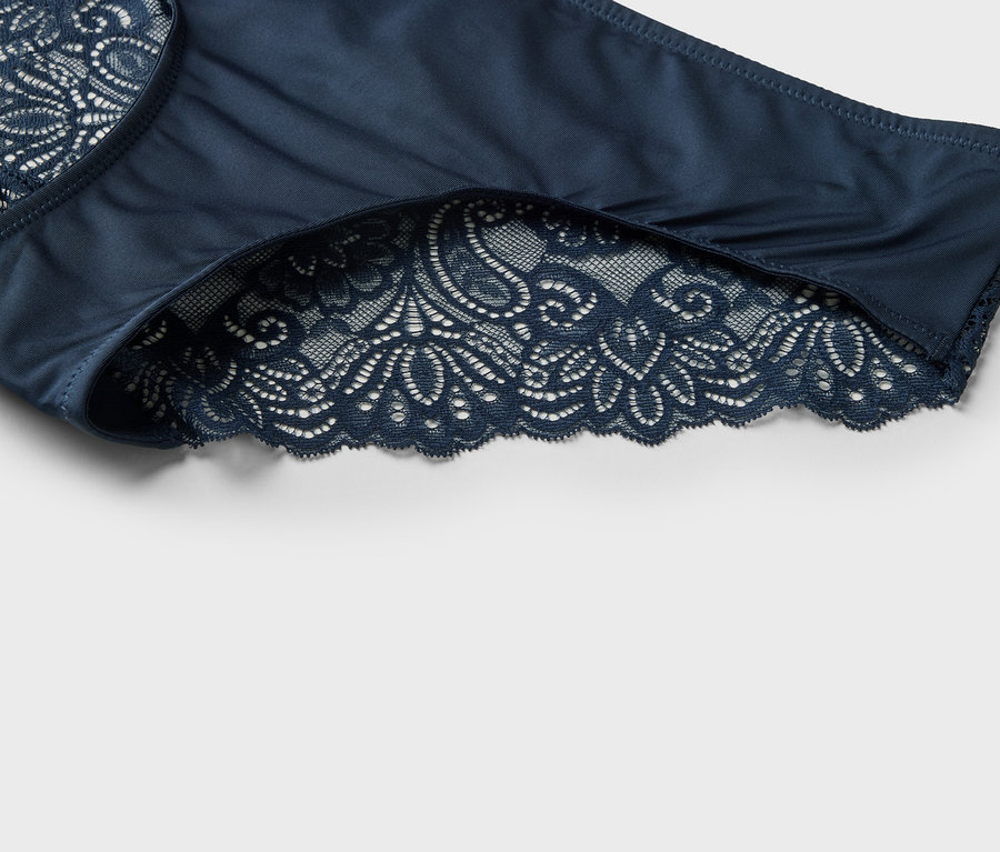 Detailní záběr na tmavě modré dámské kalhotky s krajkovým lemováním.