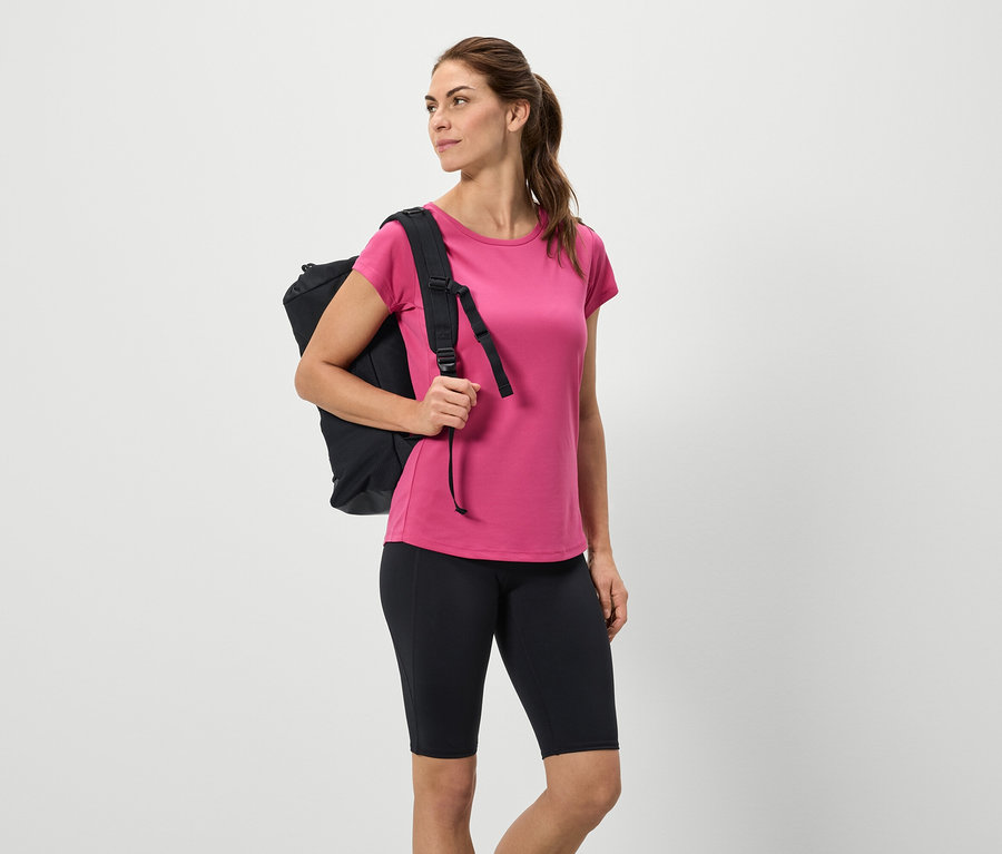 Žena s černým batohem, růžovým tričkem a černými šortkami.