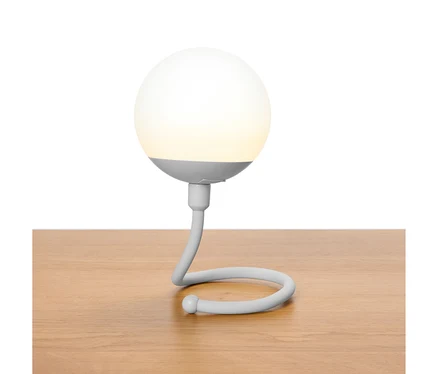 Šedá kulovitá lampa se zakřiveným krkem stojí na dřevěném stole.