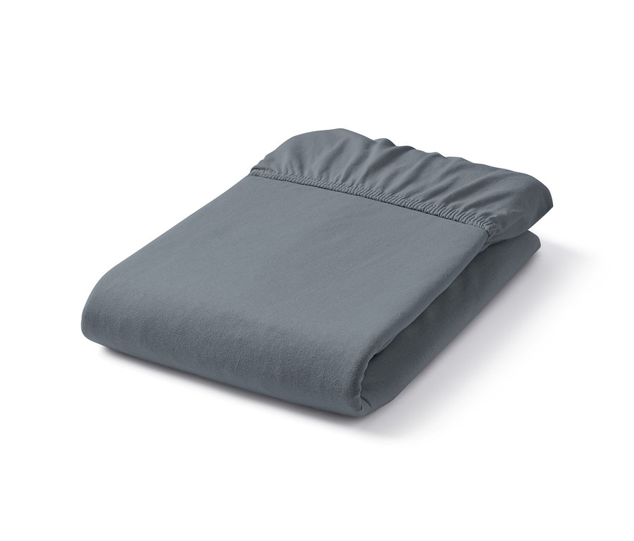 Složené šedé žerzejové napínací prostěradlo.