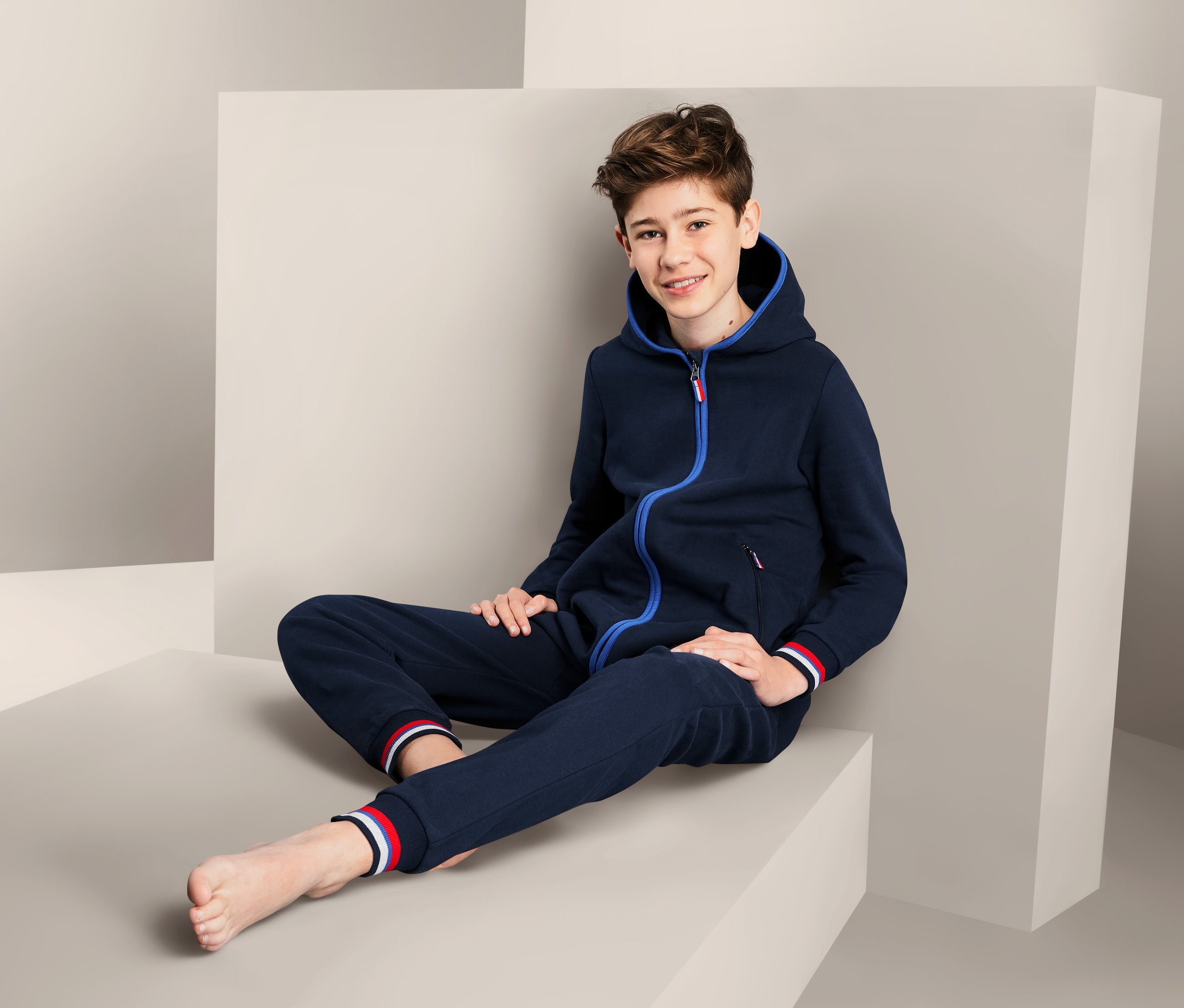 Chlapec sedí na bloku a má na sobě pohodlný overal.