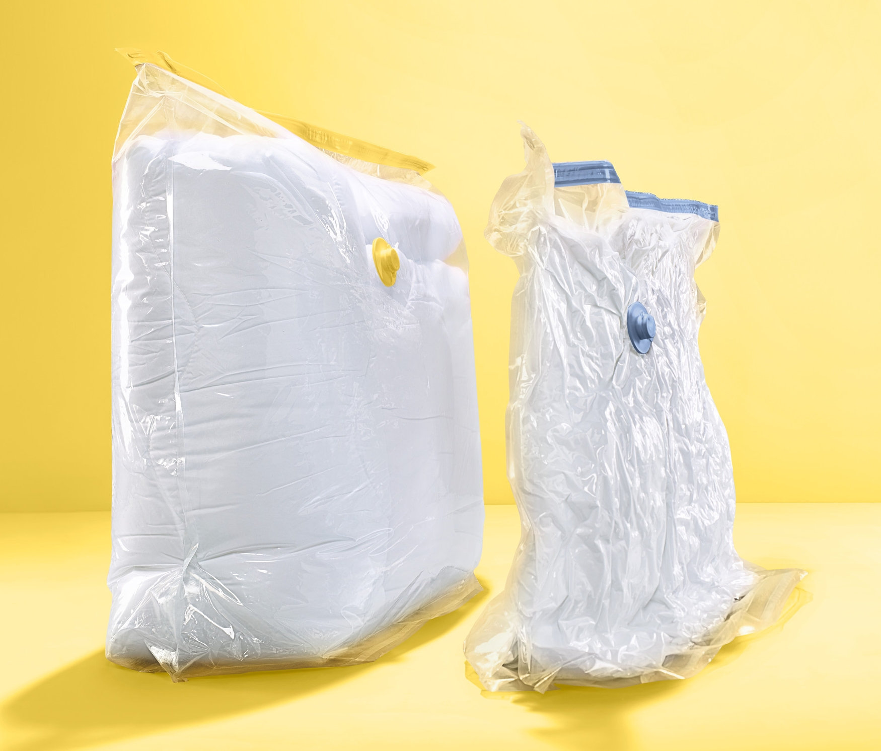 Dva vakuové úložné pytle hranaté na žlutém pozadí.