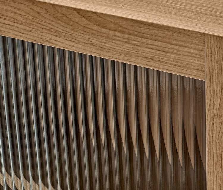 Detail nástěnné skříňky s dvířky s rýhovaným sklem.