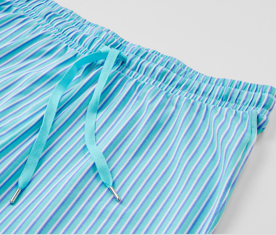 Detail pyžamových kalhot s modrými a bílými pruhy a světle modrou stahovací šňůrkou.