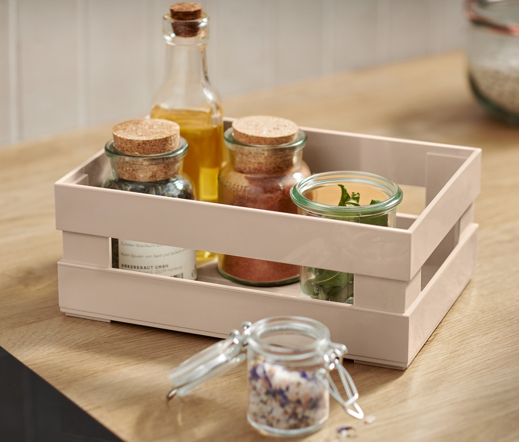 Béžový úložný box s kořením a olejem na dřevěné lince.