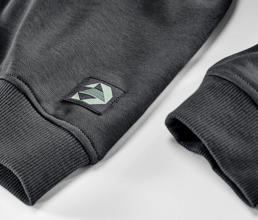 Detail dětské mikiny s počesanou vnitřní stranou, s nášivkou na rukávu.