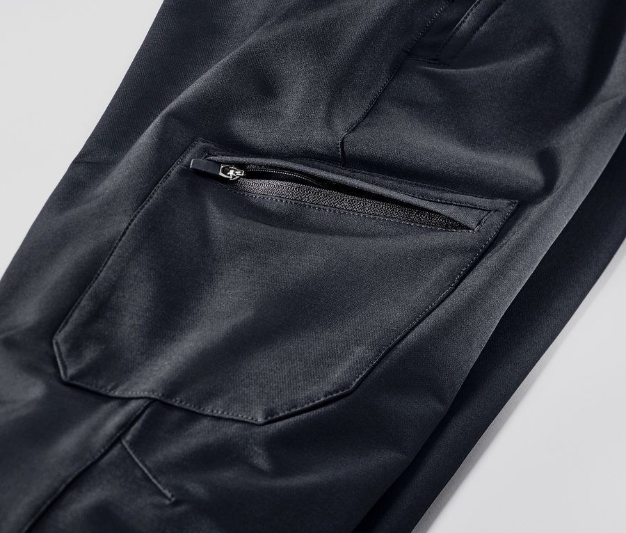 Detail softshellových cargo kalhot, černá barva, kapsa na zip.