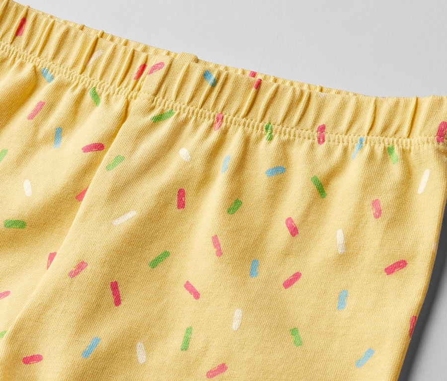 Detail žlutých dětských cyklistických legín s potiskem barevných posypek, 2 ks.