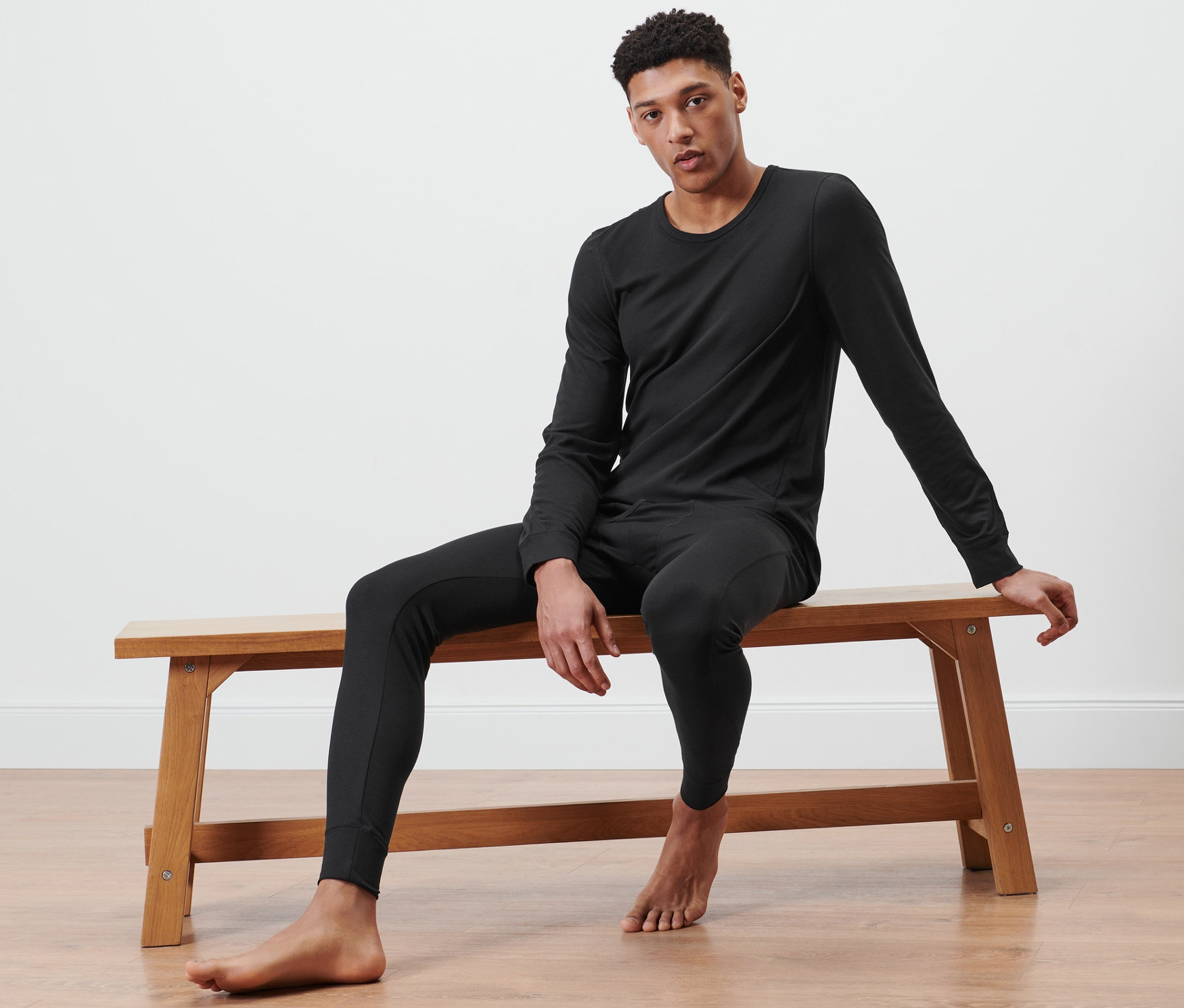 Muž sedí na lavici a má na sobě černé funkční termoprádlo.