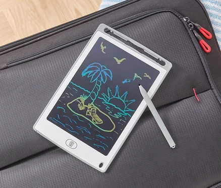 LCD psací tablet s kresbou pláže leží na šedém kufru.