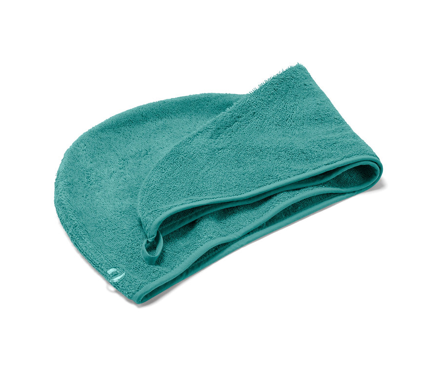 Modrozelený ručníkový turban leží na bílém pozadí.