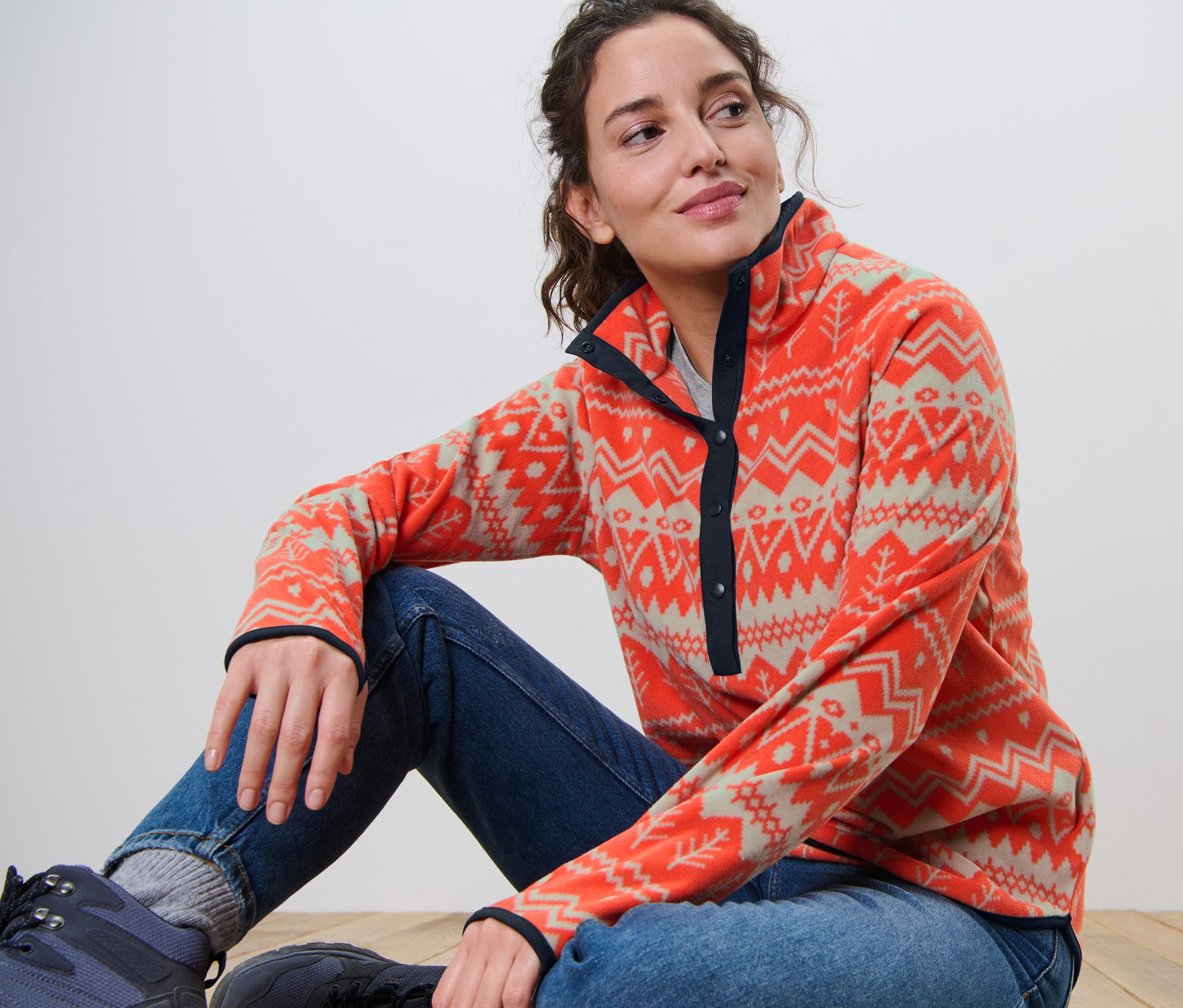 Žena sedí na podlaze a má na sobě fleecovou mikinu.