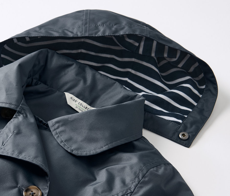 Detail dětského trenčkotu do každého počasí s kapucí s modrobílými pruhy.