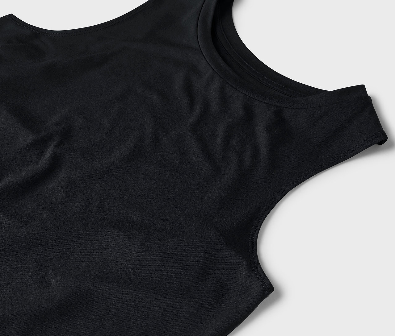 Detail černého tílka na šedém pozadí.