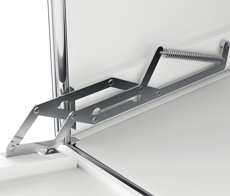 Detail stříbrného skládacího mechanismu na bílém povrchu.