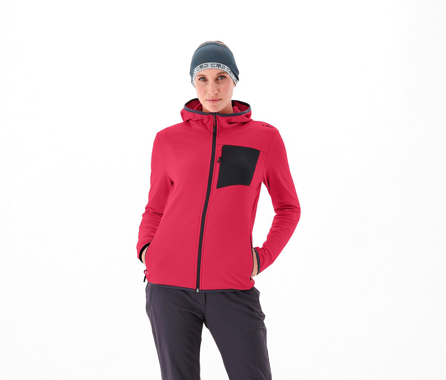Žena má na sobě červenou bundu CMP a šedou čepici.