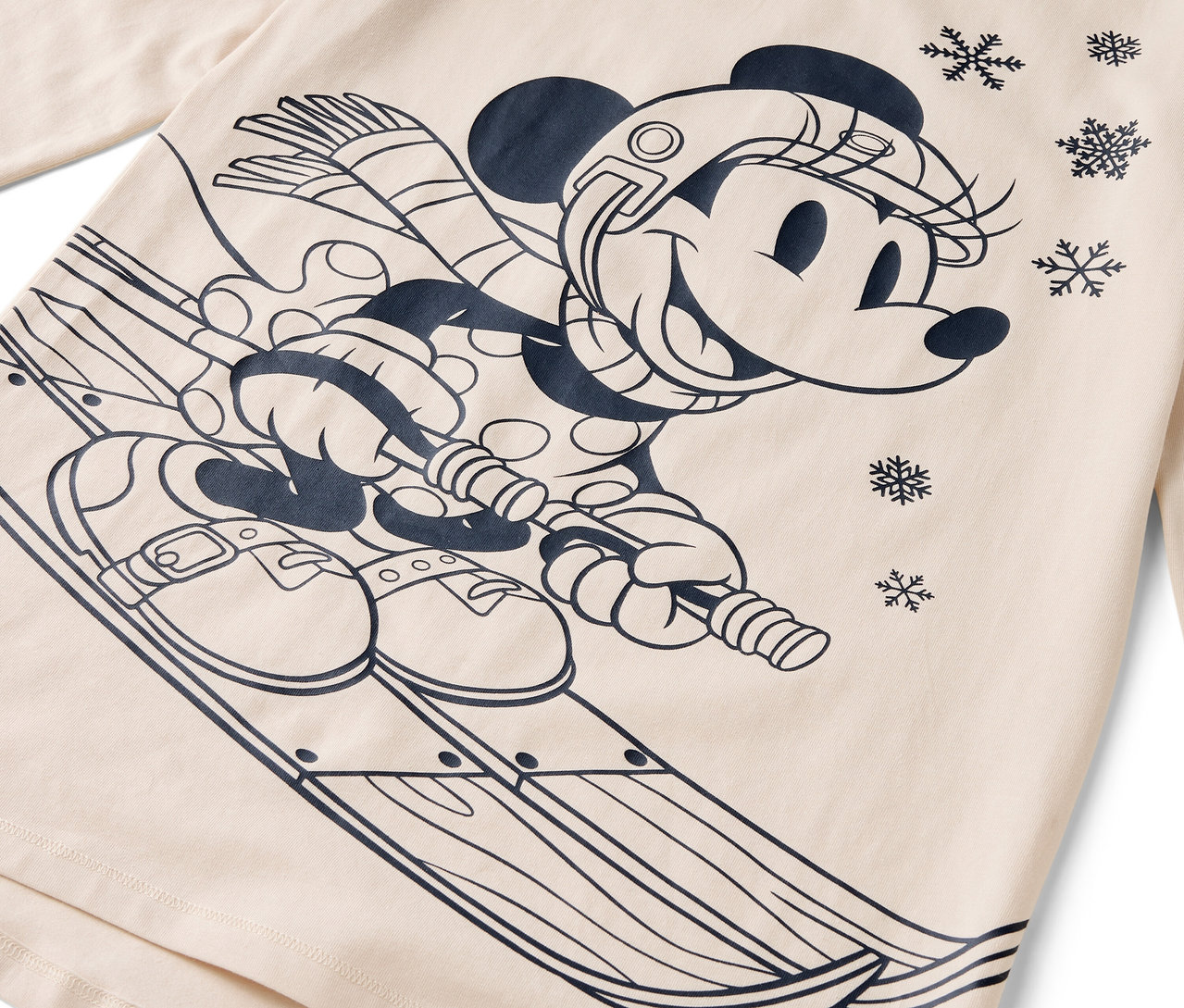 Kreslená postavička myšky Minnie na lyžích s helmou, šálou a rukavicemi na béžovém pozadí.