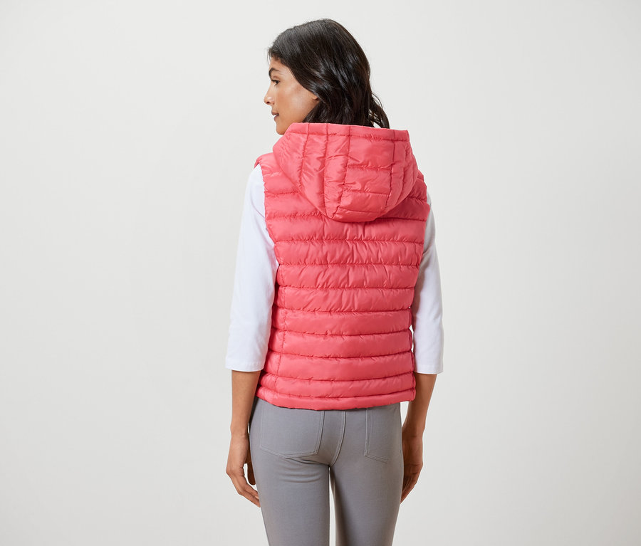 Žena má na sobě prošívanou vestu s kapucí.