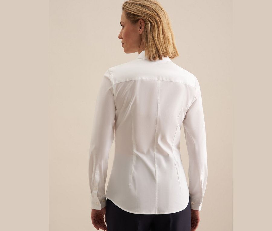 Zezadu je vidět žena s blond vlasy v bílé halence slim fit Seidensticker.