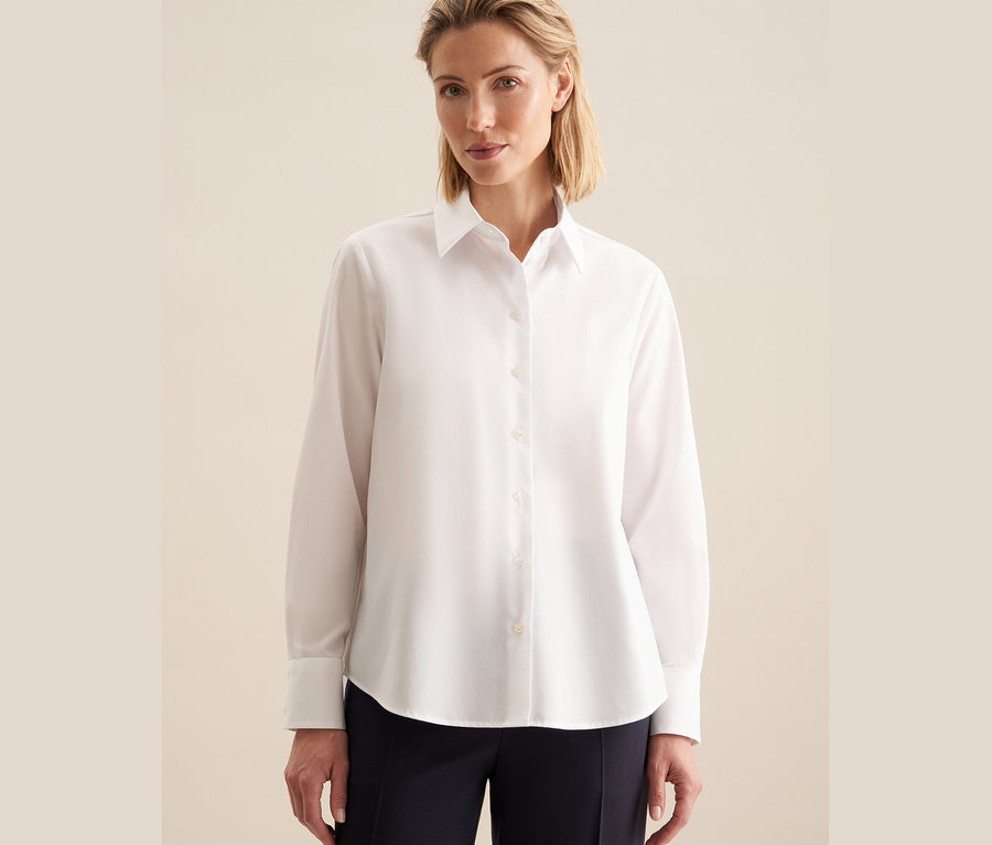 Žena má na sobě bílou nežehlivou halenku Seidensticker.