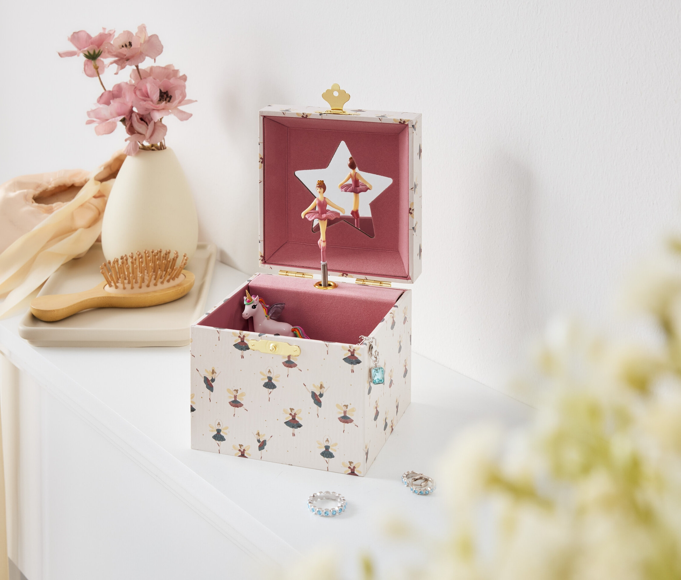 Otevřená hudební skříňka s baletkami a jednorožcem na bílém stole.