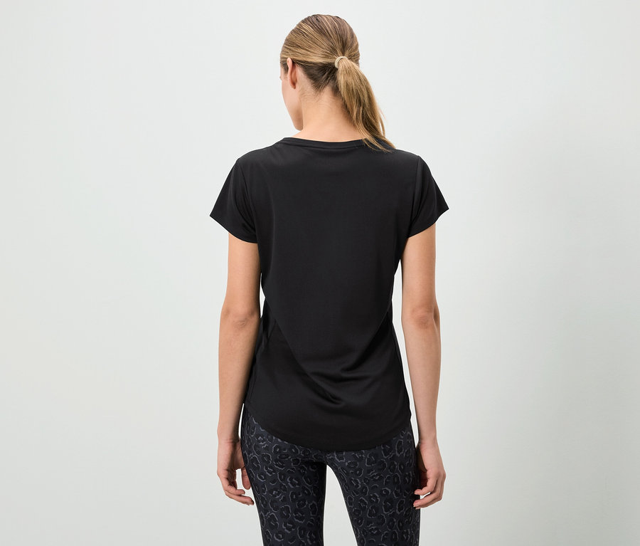 Žena zády k fotoaparátu má na sobě černé tričko a vzorované legíny.