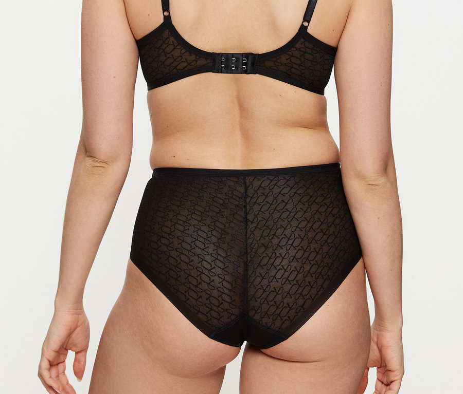 Zezadu je vidět žena, která má na sobě černou podprsenku a černé maxi kalhotky Triumph Signature Sheer Maxi EX.