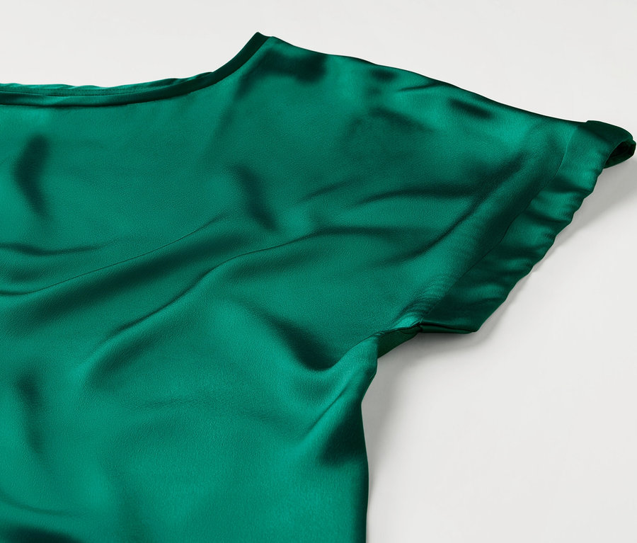 Detail modrozeleného halenkového trika z kombinace materiálů.